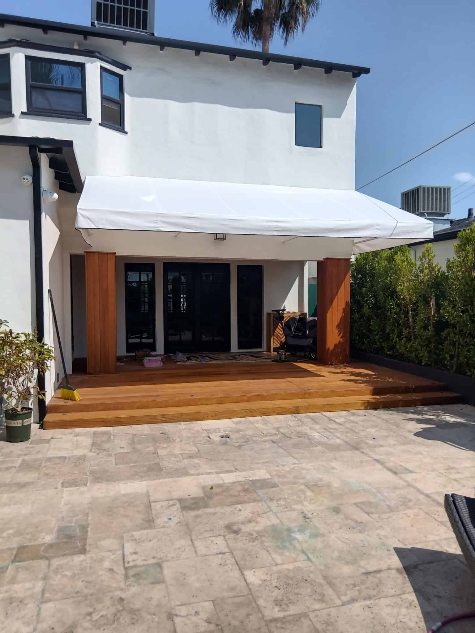 A patio featuring a white awning and a wooden deck, providing a shaded outdoor space for relaxation.