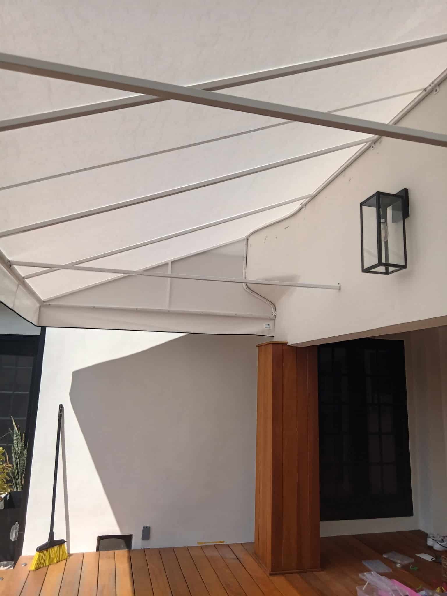 A white awning extends over a wooden deck, providing shade and shelter in an outdoor setting.
